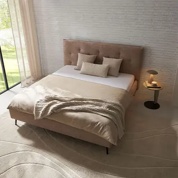 Beiges Designer Polsterbett mit gestepptem Kopfteil und Beistelltisch mit Lampe.