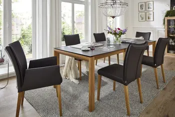 Esstisch mit schwarzer Tischplatte und Massivholz Gestell, um den mehrere schwarze Lederstühle mit und ohne Armlehne stehen.