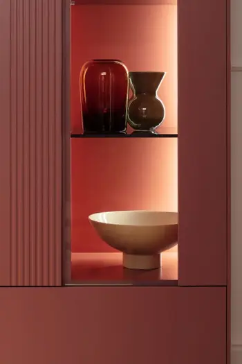 Rote Designer Vitrine mit zwei beleuchteten Regalfächern, in denen Vasen stehen.