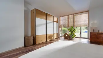 Leicht geöffneter Kleiderschrank aus Massivholz mit weißem Dekor an den Türen in der Mitte.