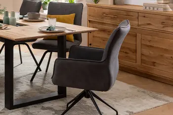 Grauer drehbarer Armlehnstuhl und graue Esszimmerstühle an einem Massivholz Esstisch.