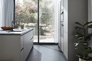 Moderne weisse Küche mit Kücheninsel in Seitenansicht.