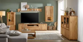 Wohnwand aus Massivholz grifflos bestehend aus TV-Board, Highboard, Wandschrank, Wandregalboden und zusätzlich noch einer passenden Vitrine mit Glasscheiben, dekoriert mit vielen Vasen, Kerzenhaltern und Pflanzen in einem gemütlichen Wohnzimmer.