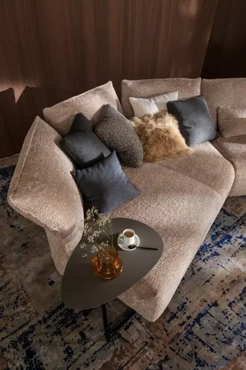 Beiges Trapezsofa mit mehreren Kissen dekoriert und einem Beistelltisch.