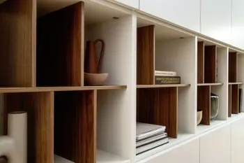 Wohnwand in weiß, in der ein Regal mit hochkanten Regalböden enthalten ist die abwechselnd in weiß und holzfarben sind.