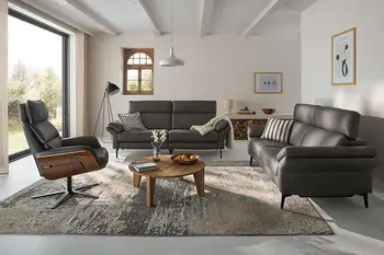 Zwei graue Design Ledersofa Garnituren mit hoher Rückenlehne und Relaxsessel in einem hellen Raum. 