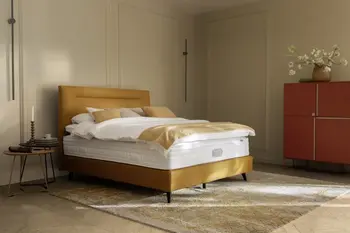 Zwei Designer Beistelltische in rot und schwarz neben einem gelben Boxspringbett.