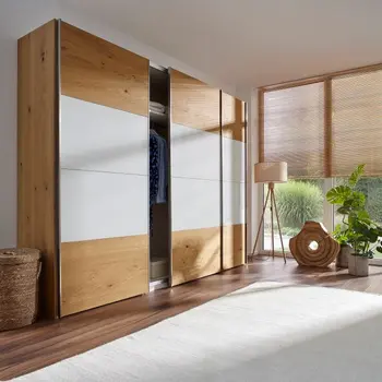 Leicht geöffneter Kleiderschrank aus Massivholz mit weißem Dekor an den Türen in der Mitte.