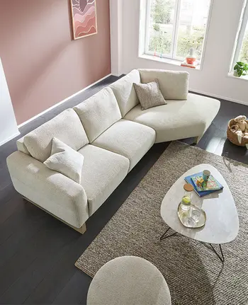 Weißer Couchtisch vor großem beigen Sofa in hellem Wohnzimmer.