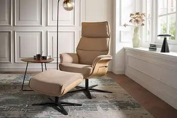 Beiger Design Relaxsessel mit Holzschale an den Armlehnen und farblich dazu passendem Hocker.