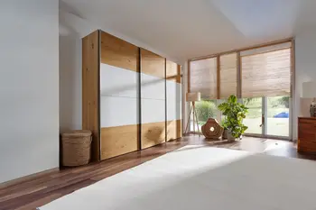 Heller Kleiderschrank mit grauen Glaselementen.