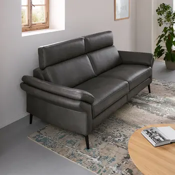 Graue Design Sofa Garnitur mit hohen Rückenlehnen und Kopfstützen in einem hellen Raum.