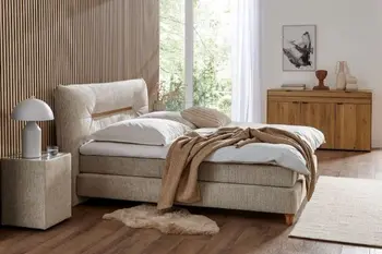 Beiges Boxspringbett vor einer Wand mit Akustikpaneelen in einem hellen Schlafzimmer.