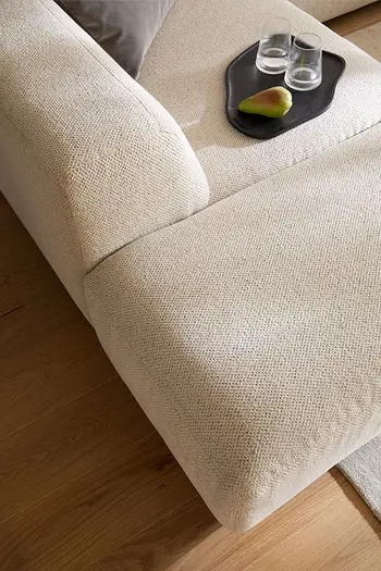 Detailbild von Abschlusselement eines beigen Ecksofas mit niedriger Rückenlehne.