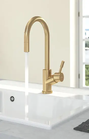 Weiße Keramikspüle mit Goldenem Wasserhahn.