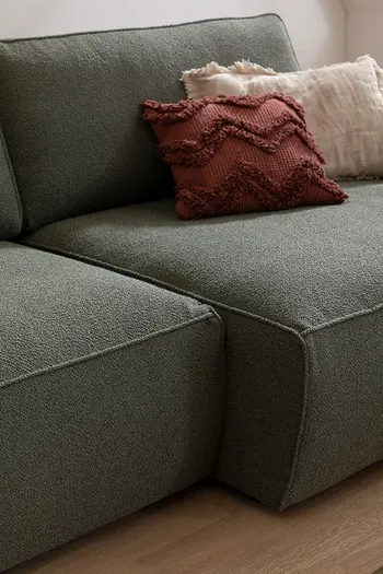 Extrabreite Sitzfläche eines Sofas mit grünem Stoffbezug.