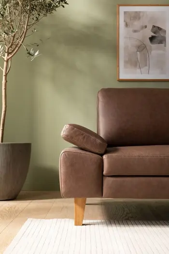 Linker Teil eines braunen Ledersofas mit klappbaren Armlehnen und Holzfüßen.