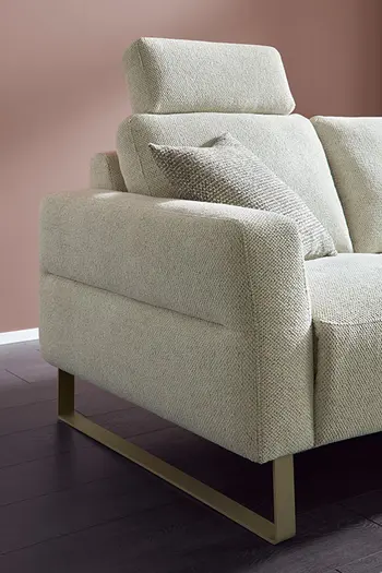 Beiges Stoffsofa mit silberner Metallkufe und Kopfstütze.