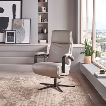 Grauer Leder Relaxsessel mit schwarzem Sternfuß vor großen Fenstern.