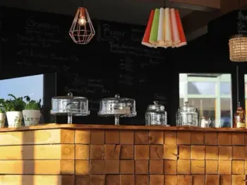 Theke mit Gläsern, Töpfen und Tortenplatten mit Hauben im Pavillon vor dem wöm