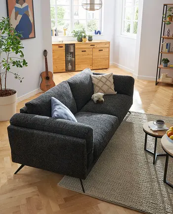 Modernes 3-Sitzer-Sofa in dunkelgrauem Stoffbezug freistehend in modernem Wohnzimmer.