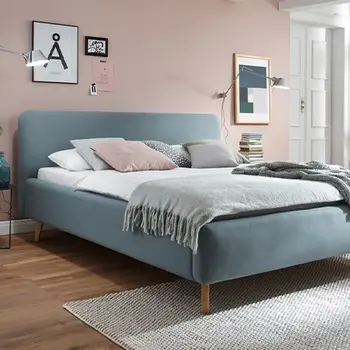 Blaues Bett in einem jung eingereichten Raum mit weichen Farben