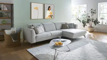 Hellgraues Ecksofa mit filigranen schwarzen Füßen und einem eleganten dreieckigen Beistelltisch.