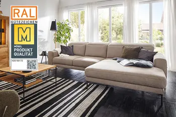 Siegel "Goldene M" auf einem Bild eines modernen beigen Ecksofas mit schwarzem Fußgestell und umgeklappter Rückenlehne.