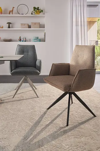 Zwei Armlehnstühle in blauem und braunem Stoffbezug an Esstisch.