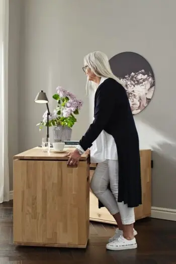Frau steht an einem Sideboard und schiebt es auseinander um einen Schreibtisch zu erhalten.