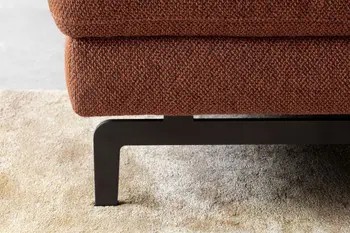 Schwarzes Metallfußgestell eines rostroten Sofas.