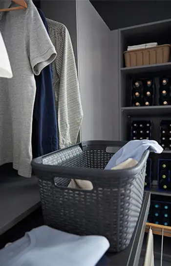 Wäscheschrank in einem grauen Hauswirtschaftsraum mit ausziehbarer Ablage.