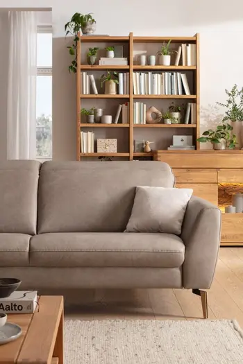 Rechte Seite eines 2,5-Sitzer Sofas in grauem Leder in einem hellen Zimmer.