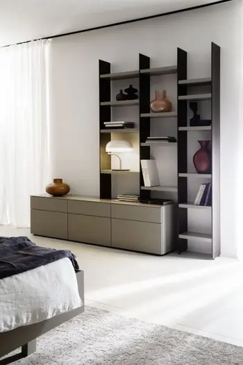 Regalwand mit schwarzen Rahmen und grauen Einlegeböden, das an einem Sideboard in grau befestigt ist und mit Vasen, Büchern befüllt ist.