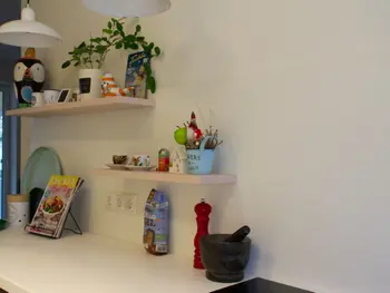 Wandregaler mit hübscher Dekoration in gelber, farbenfroher Küche