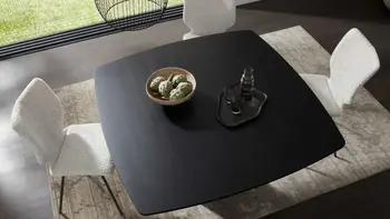 Moderner, quadratischer Esstisch in schwarzer Eiche in hellem Esszimmer mit weißen Stühlen.