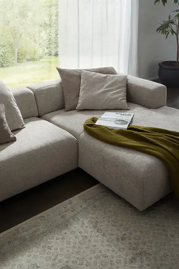 Longchair eines beigen Design Ecksofas mit niedriger Rückenlehne.