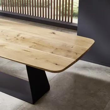 Esstisch aus massiver Eiche mit abgerundeter Tischplatte und schwarzem Metallgestell.