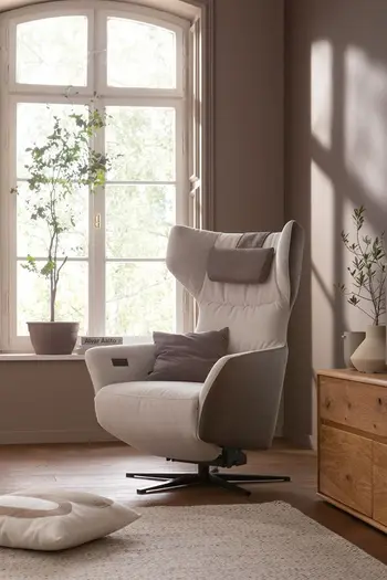 Beiger Relaxsessel mit Kissen im Kopfteil und braunem Kissen auf der Sitzfläche.