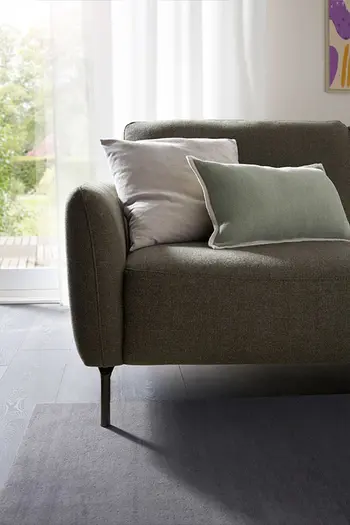 Detailbild von einer schmalen Armlehne von einem dunkelgrünem Stoffsofa.