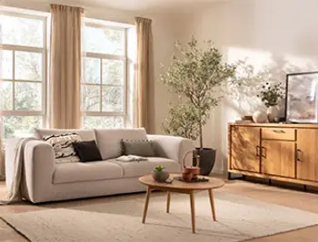 Beiges Zweisitzer Sofa, Massivholz Couchtisch und Sideboard in einem hellen gemütlichem Raum.