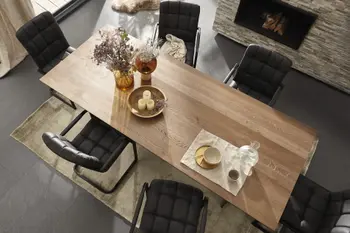 Großer Esstisch mit Tischplatte aus Eichenholz und schöner Marmorierung, um den gesteppte Freischwinger aus schwarzem Leder stehen.