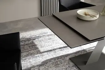 Moderner schwarzer Esstisch, bei dem die Verlängerung leicht unter dem Tisch hervorschaut.