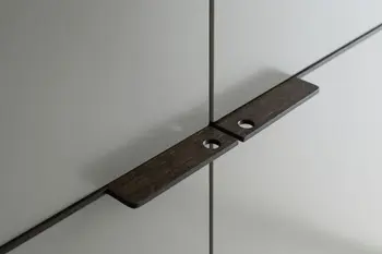 Flache schwarze Griffe eines modernen grauen Kleiderschranks.