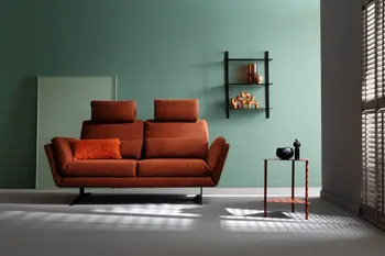 Wohnzimmer mit rotem 2-Sitzer-Sofa vor grüner Wand mit schwarzem Regal und Beistelltisch.