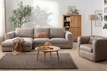 Graues Ecksofa in einem gemütlichen Wohnzimmer mit einem runden Couchtisch aus Holz und einem modernen Sessel aus grauem Leder.