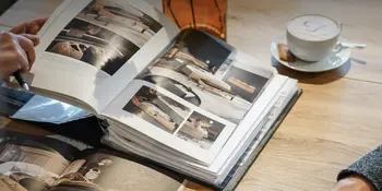 Geoeffneter Katalog auf Holztisch im Moebelhaus Reichenberger neben Tasse Cappucino.