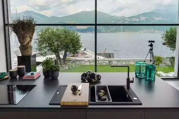 Schwarze Verbundstoff-Spüle mit Ablagefläche vor einem großen Fenster.