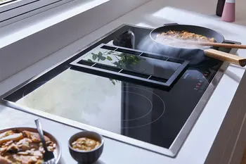 Modernes Kochfeld mit runden Kochzonen und integriertem Dunstabzug.