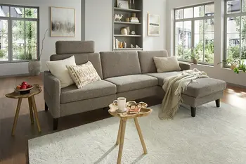 Gemütliches, graues Ecksofa mit Stoffbezug in hellem Wohnzimmer.